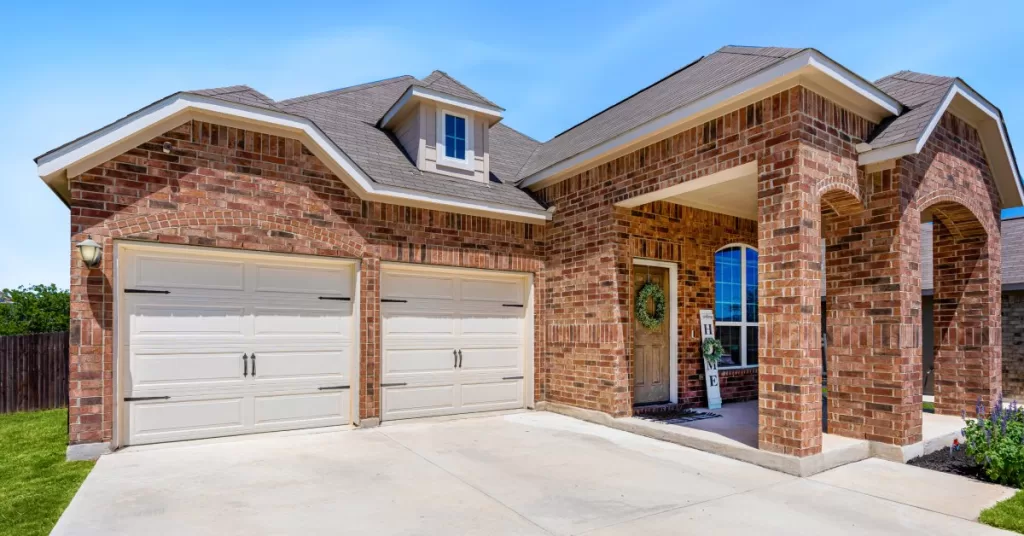 A brick suburban house with two arches near the front porch and a double-wide garage with two single doors.