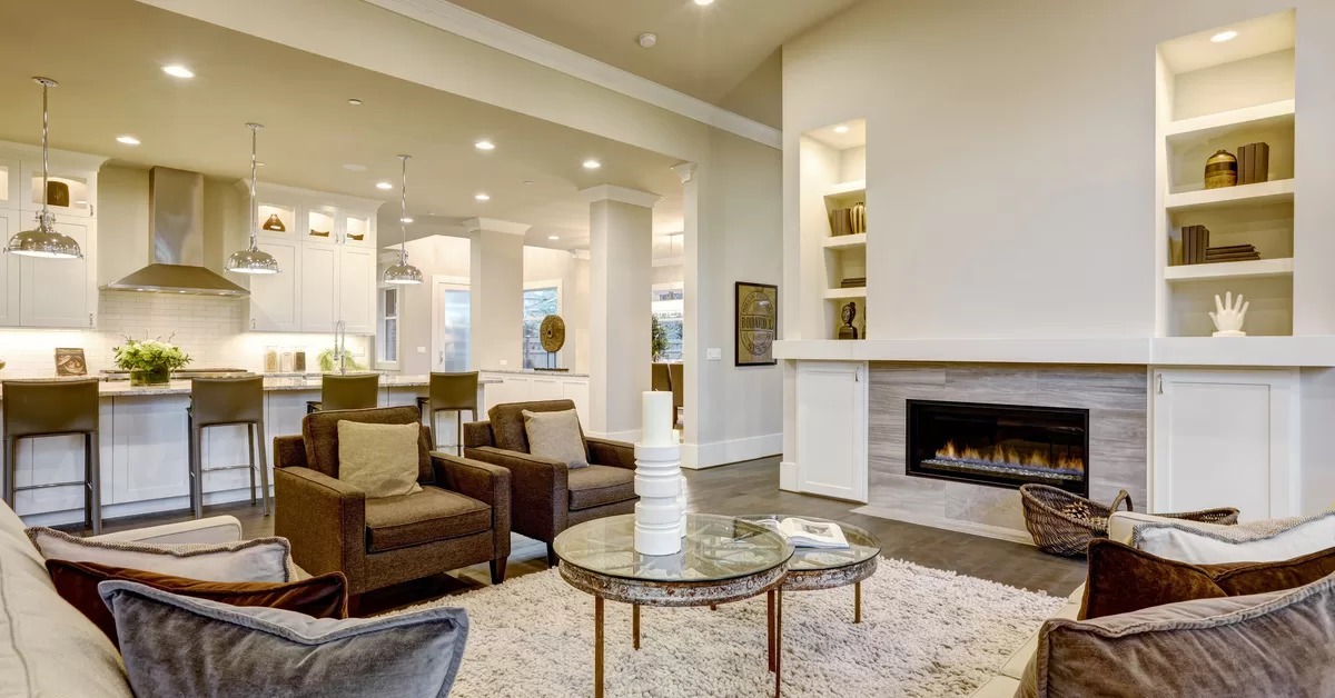 A chic living room interior with an open floor plan. The room features loveseats and chairs facing each other and a fireplace.