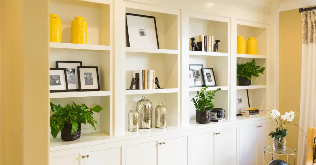 Several built-in shelves and sets of cabinets in a common area. The shelves display picture frames and decor.