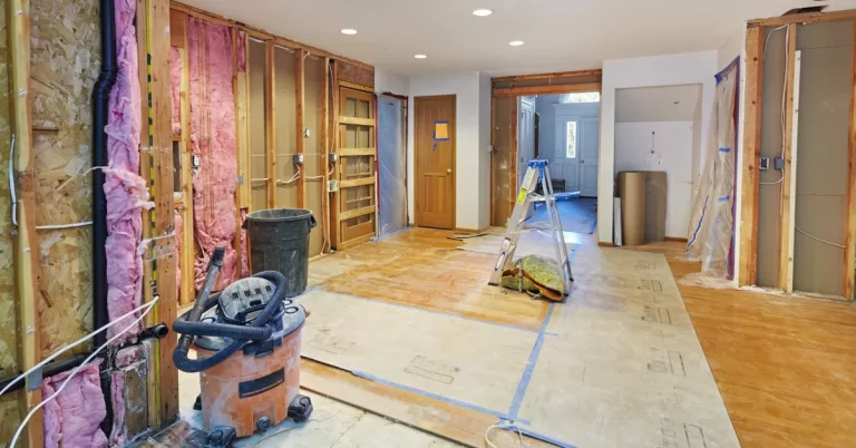 A home common area in the middle of a renovation with exposed framing, wiring, installation, and incomplete flooring.